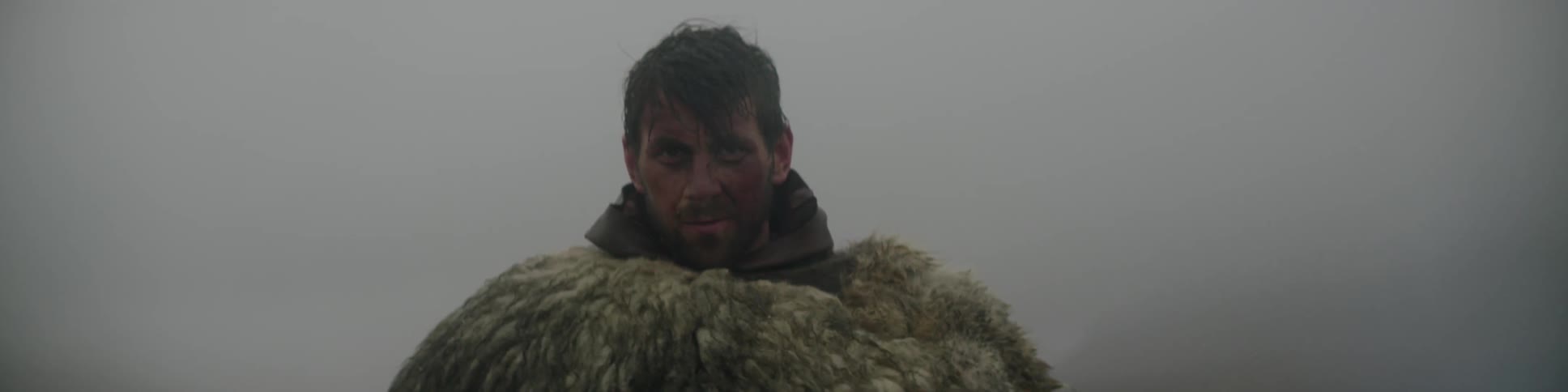 Close up of a man wearing a fur with a dirty face