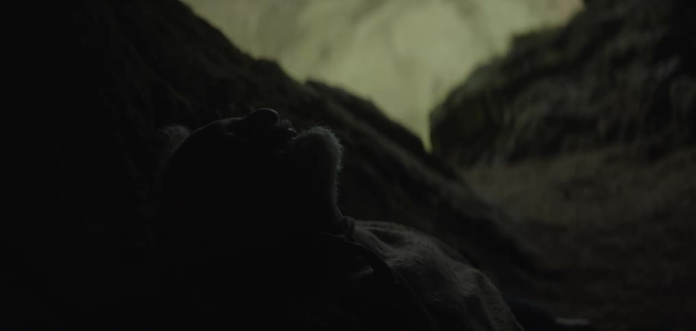 A man lays down in a cave and screams