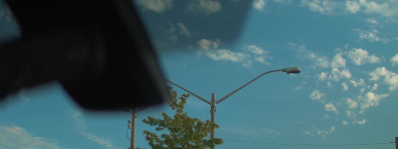 A vehicles sunroof provides clear views of the sky and trees outside