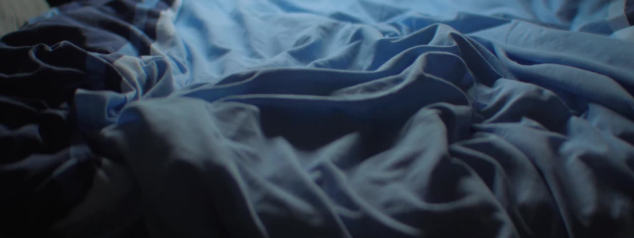 Rumpled blue patterned bedspread sits on bed
