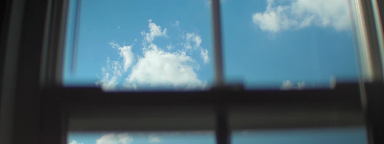 White clouds in the blue sky on a sunny day seen from behind the windows