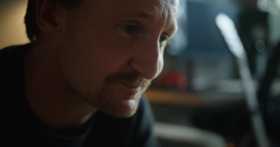 Man sitting and looking down covers mouth with hand