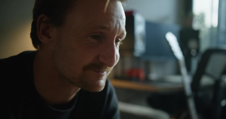 A man sits in his living and blows a kiss during a conversation