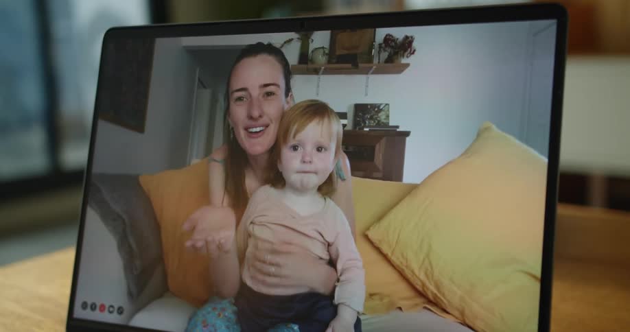 A woman and baby are seen in a video call waving to the other viewer