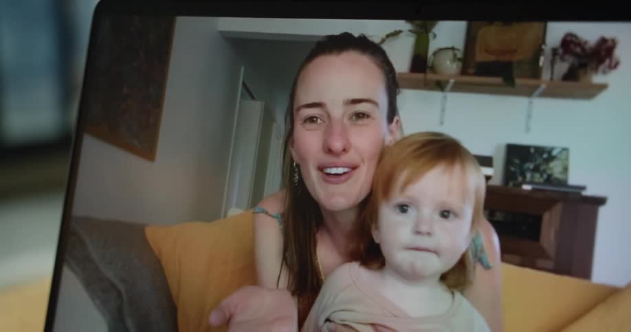 A mother and daughter are shown on a video call on a laptop waving and blowing a kiss
