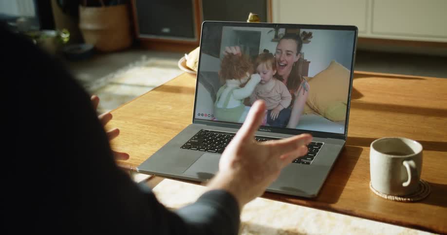 A man talks to a woman via video call on his laptop who shows off a doll her daughter received as a gift