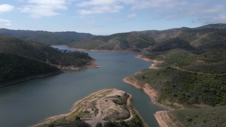 Aerial view of river surrounded by hills with a blue sky