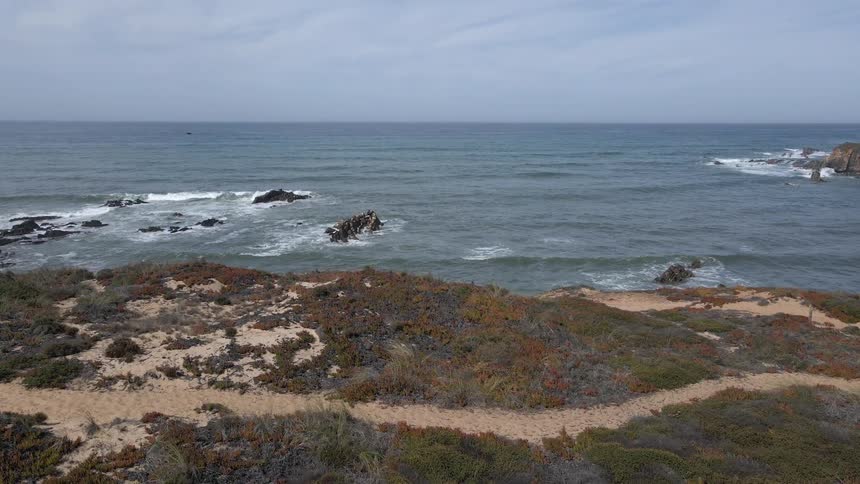 Small path on the top of a cliff next to the ocean at day time