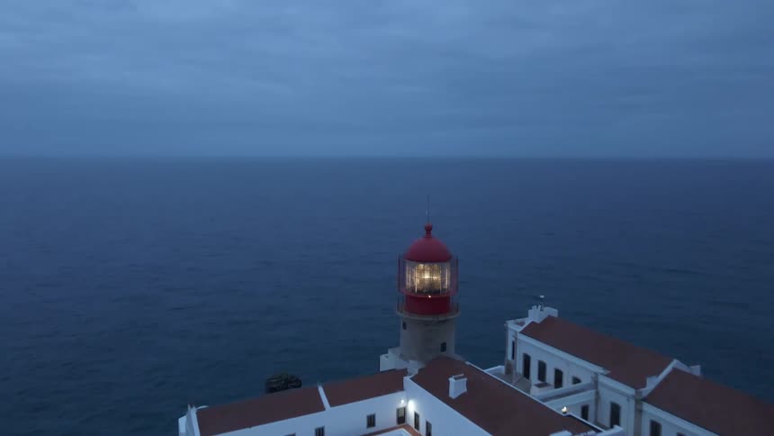 Lighthouse and building complex on the peak of a rocky outcropping near the ocean