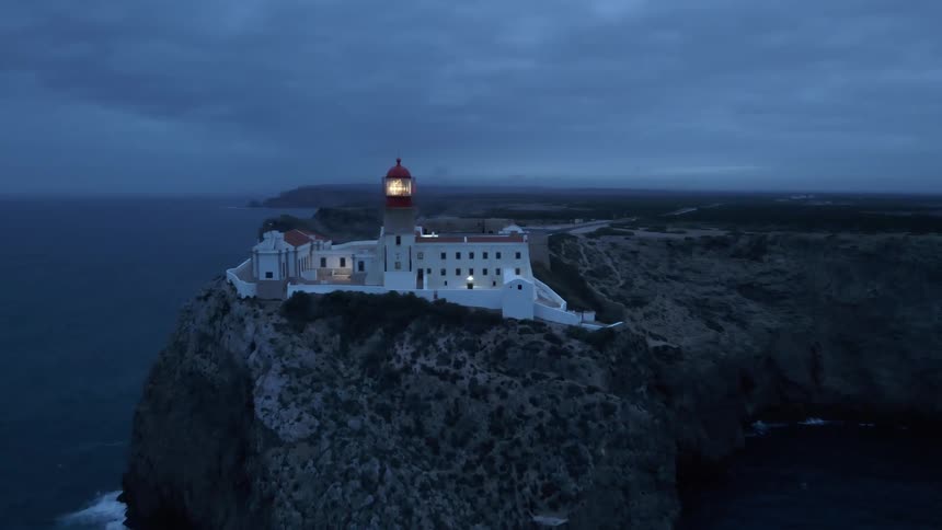 Rotating light house light in the center of a building complex on the edge of a sea side cliff