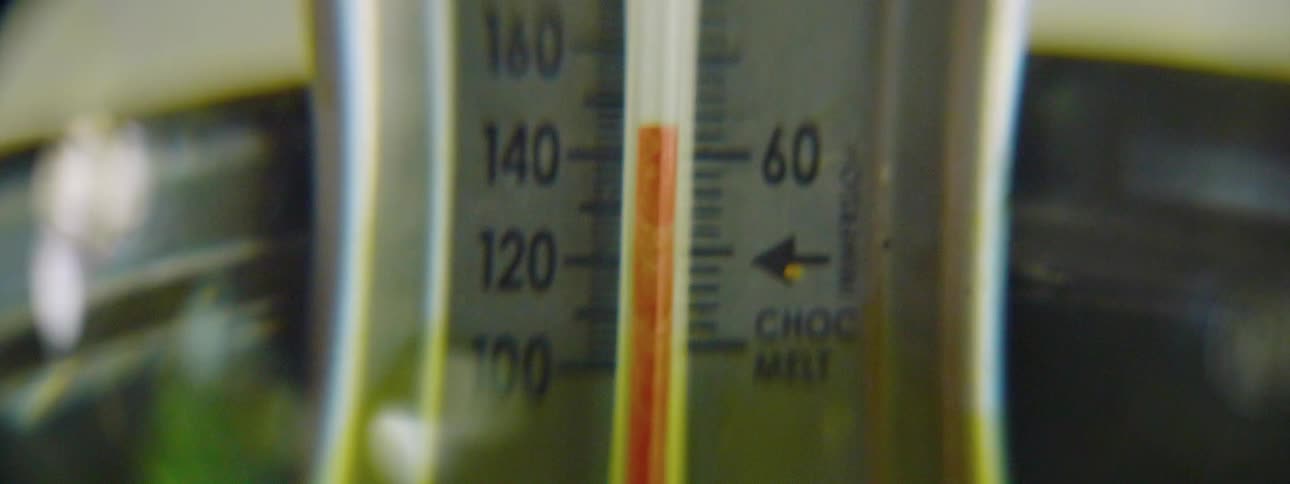 A candy thermometer sits in a metal pot