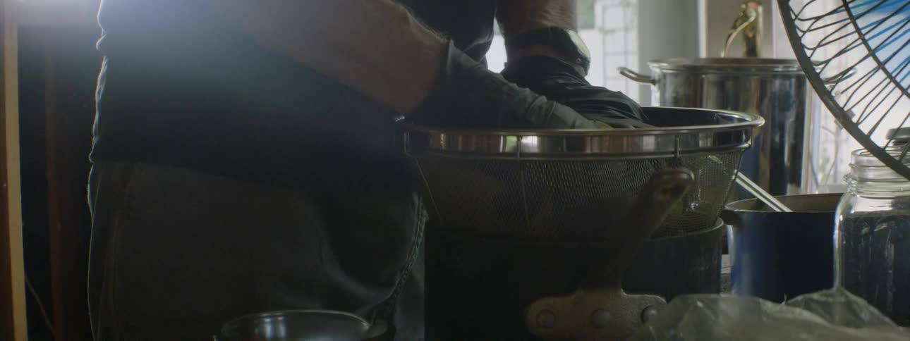 Human using sieve to get liquid out of food