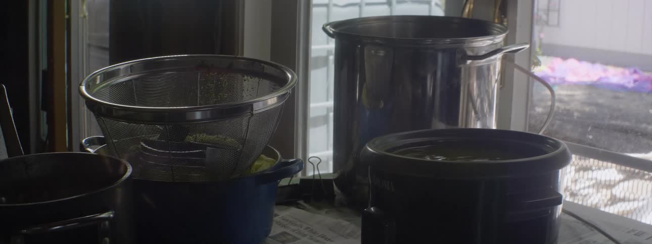 Pot of liquid boils on a stove that has other pots and a colander on it