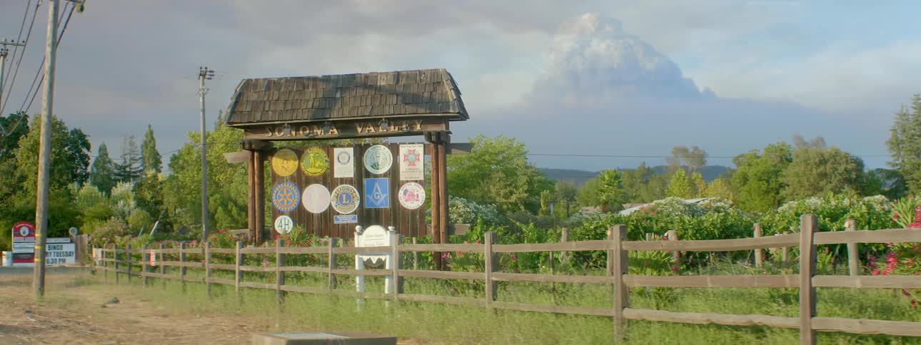 A wooden signboard has a number of organization logos attached to it