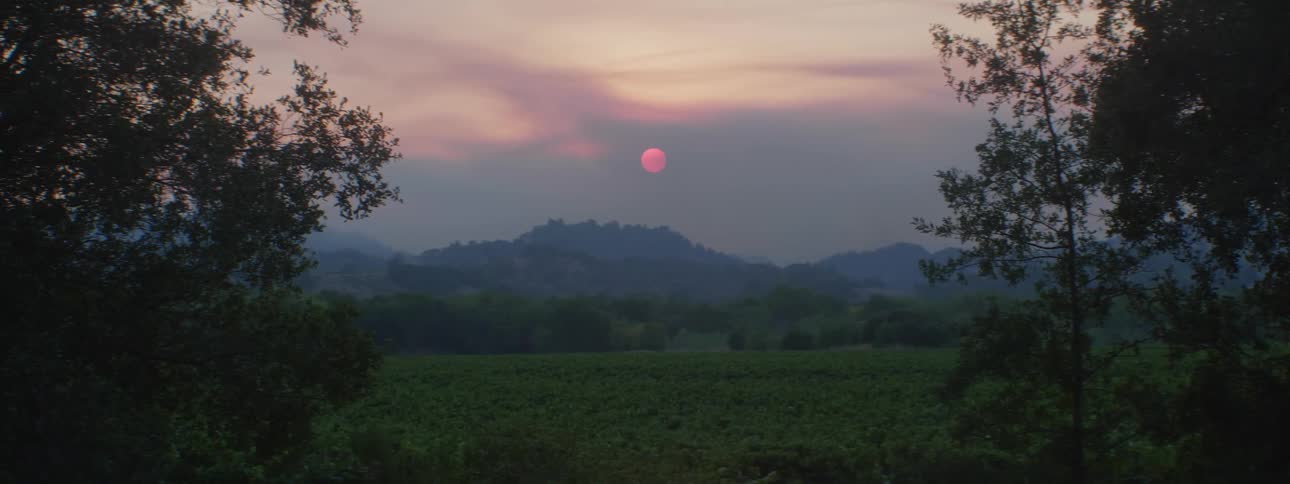 Red moon up in the sky during the daytime above distant mountains