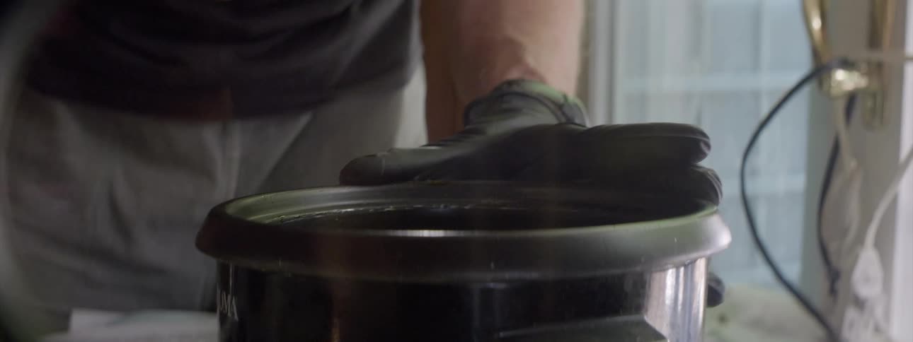Cook holds pot as he stirs contents with a spatula
