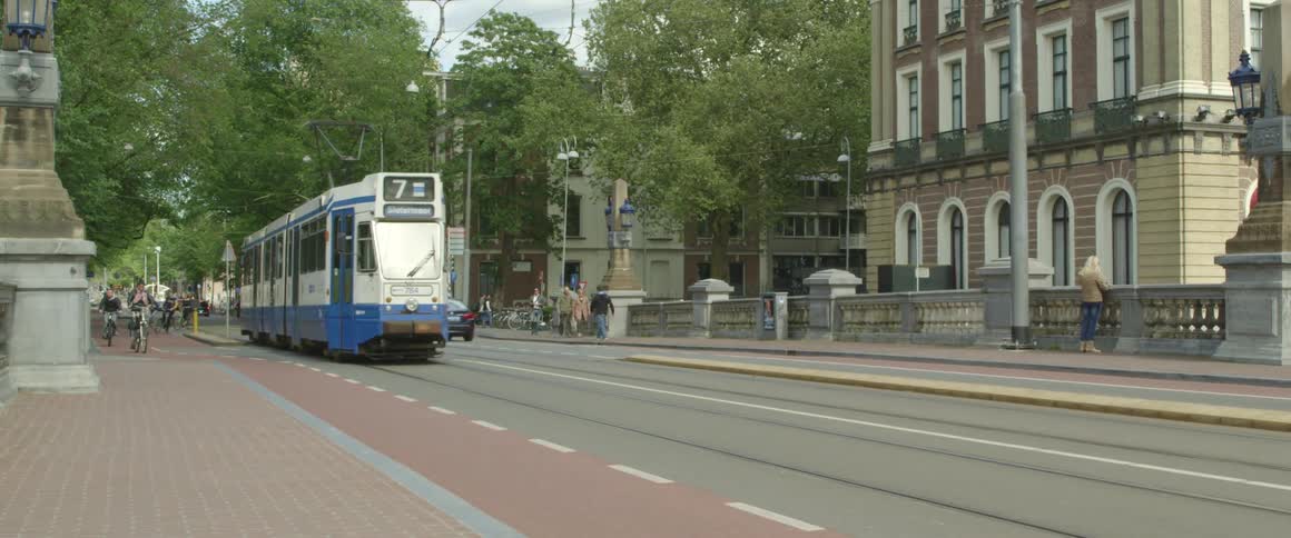 People riding bikes down a busy street in a city next to a moving trolley