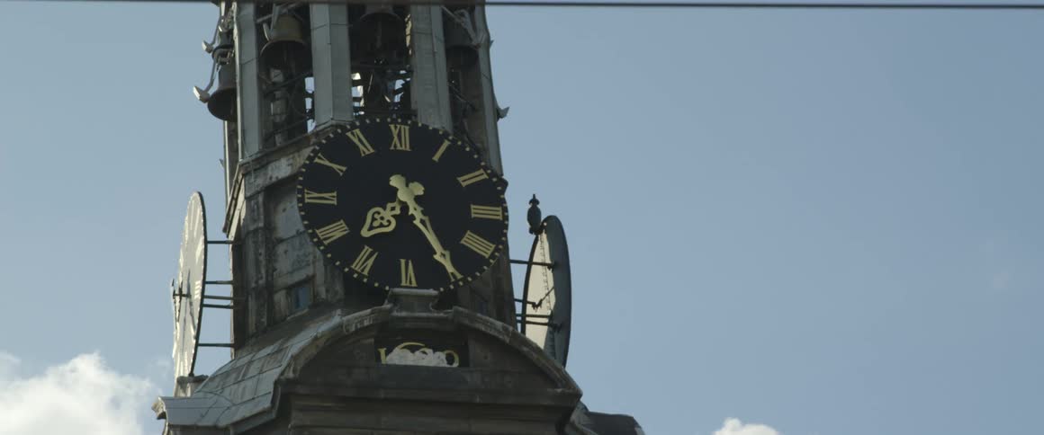 A clock tower with gold colored roman numerals on a black face against a blue sky