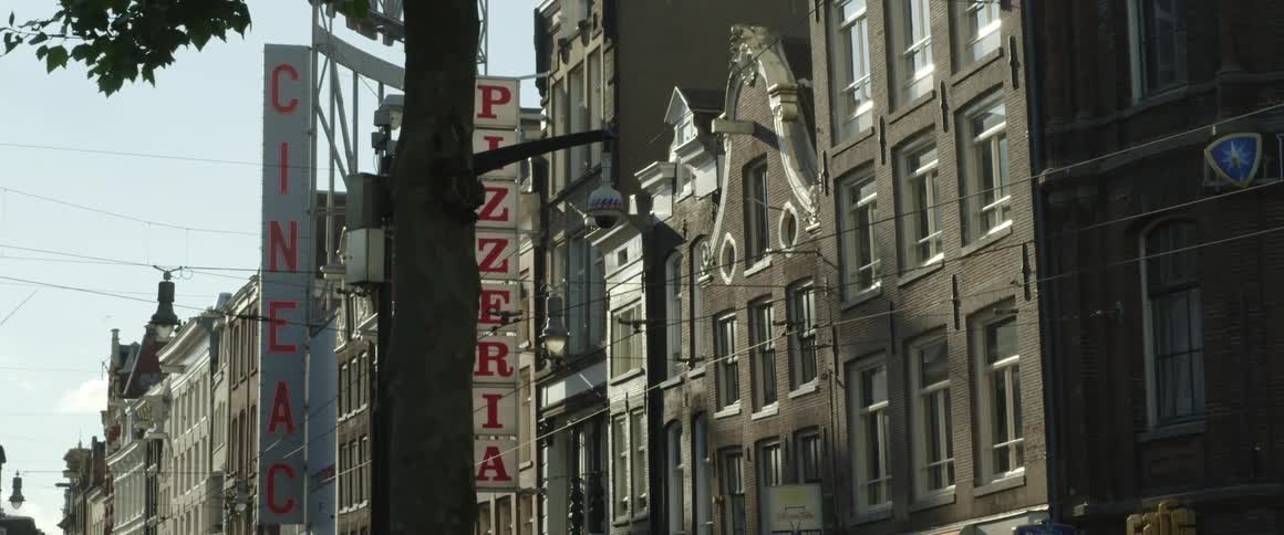 Large sign designating pizzeriastands near low rise buildings under clear sky