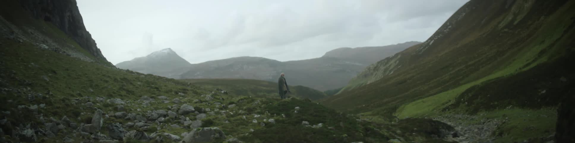 A person standing on a small hill in the mountains