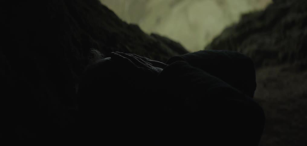 Older man laying and crying alone in a cave