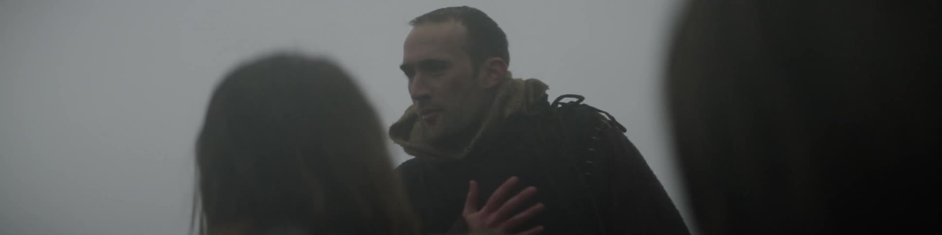 A group of people stand outside in the fog