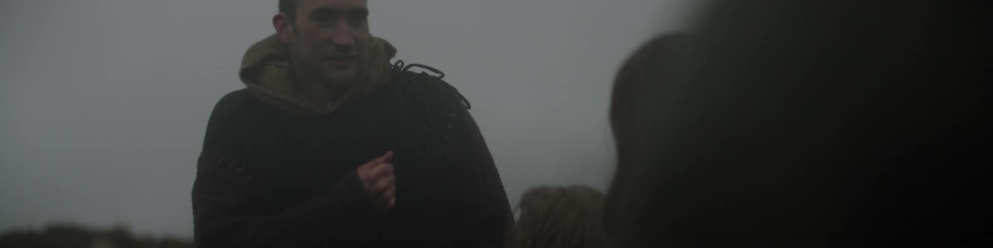 A man is speaking outside in front of others on a foggy day
