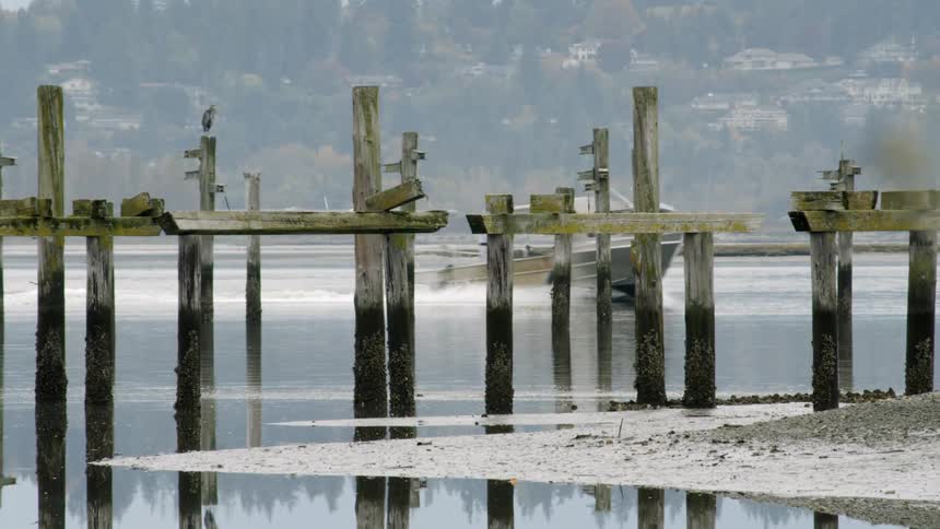 A boat is on the water moving past a damaged dock