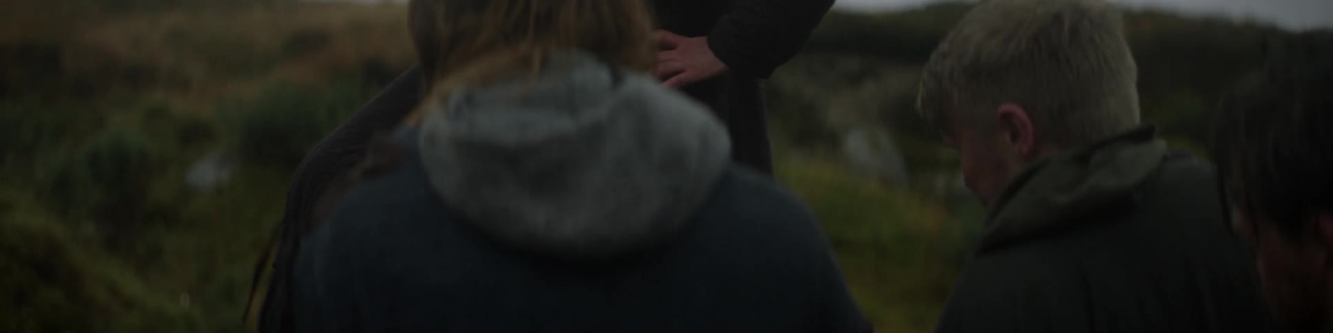 A group of people gather outside in a field