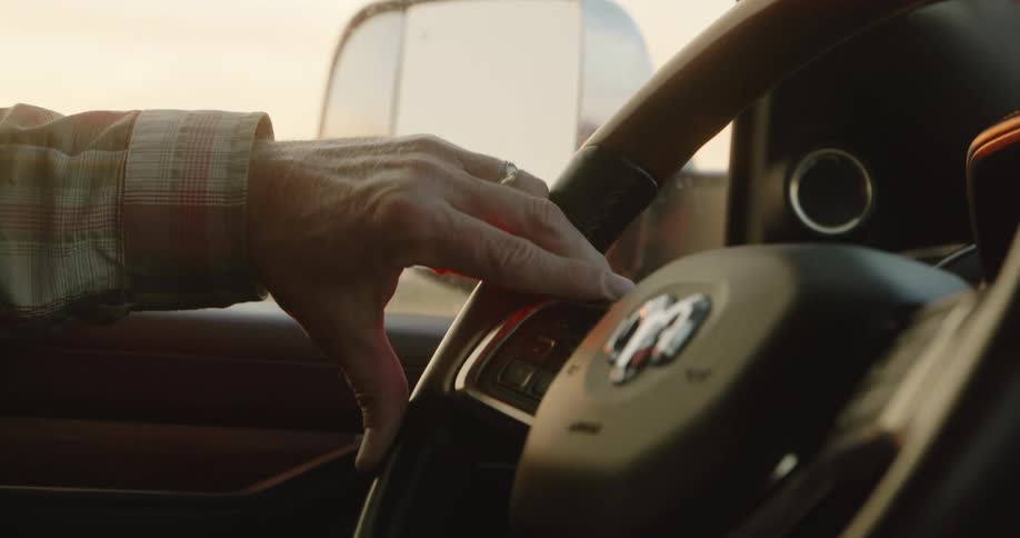 A man drives with his arm resting on the open window of his dodge car