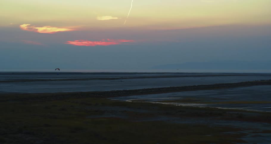 Low tide with a bird flying across a darkening sky