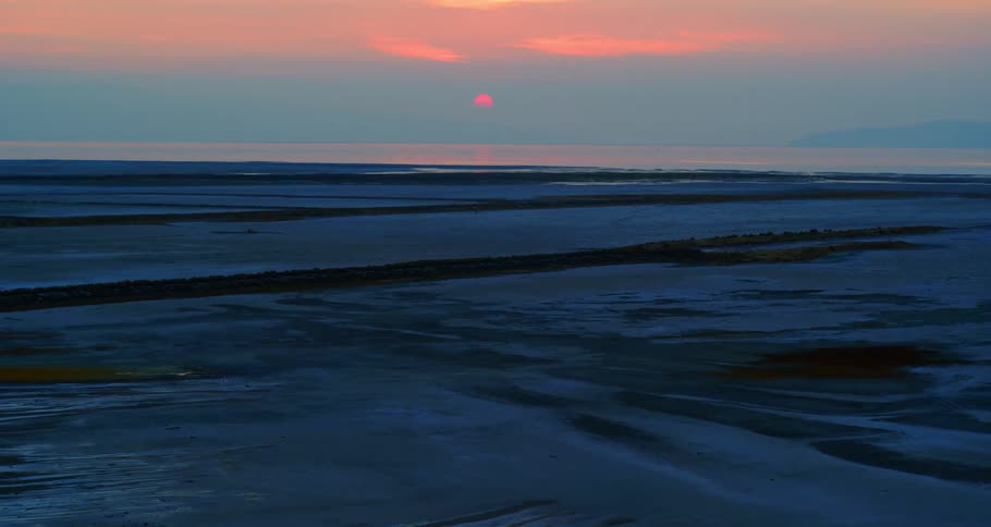 Dark blue surface stretches to horizon under red sky