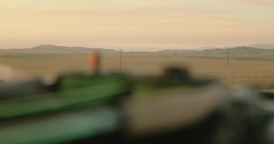 Twine on top of a moving vehicle in front of a wide field with mountains in the distance
