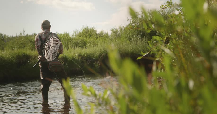 Fisherman standing in water and casting his fishing rod repeatedly