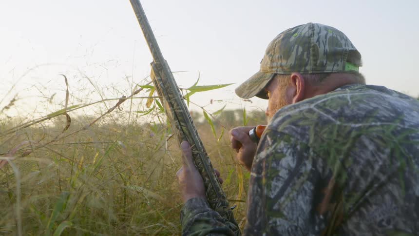 A man is on a field hunting with a whistle and gun
