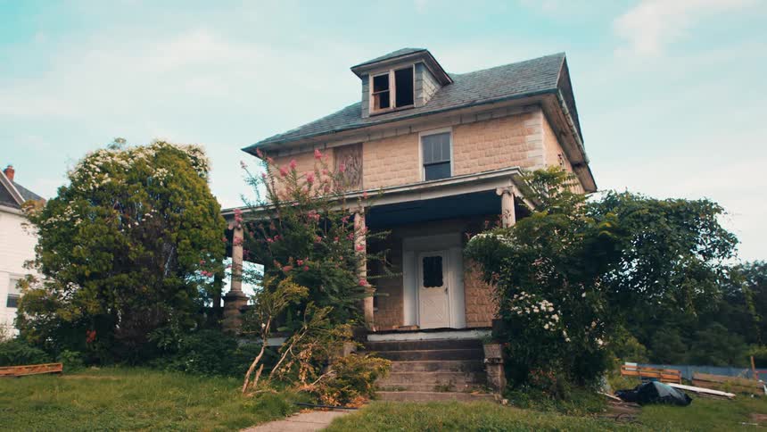 Abandoned old house in a suburb with plant overgrowth in the day
