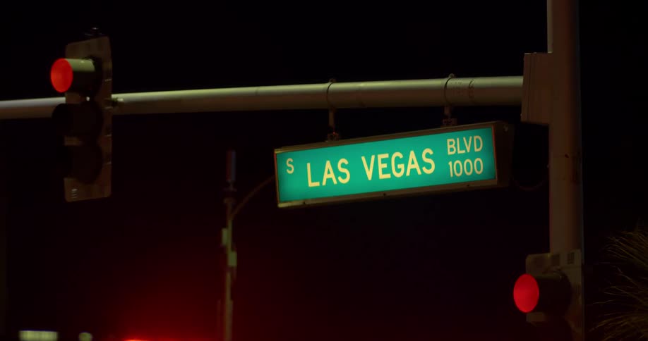 A street sign hangs next to a redcolored traffic light