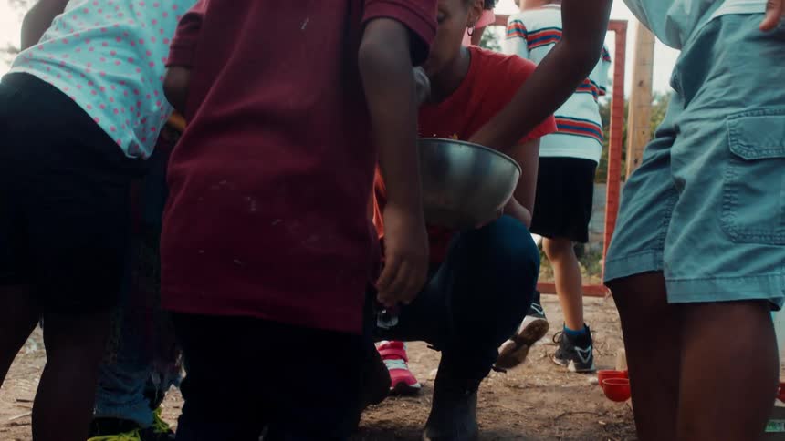 A young woman in a rural area gives grain to children