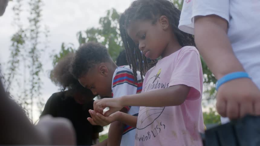 Children plant seedlings in small cubed trays outdoors