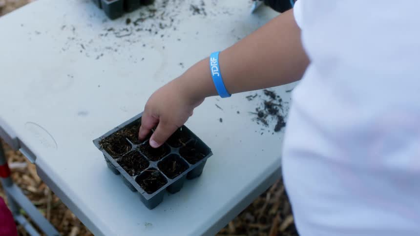 A man helps children plant crops in small containers