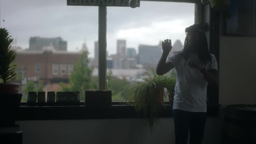 A man spins around in his apartment near downtown while using a virtual reality headset