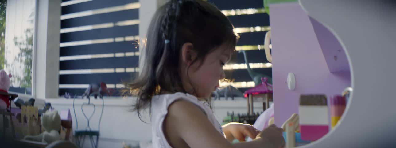 A young girl plays with a toy kitchen set on her porch