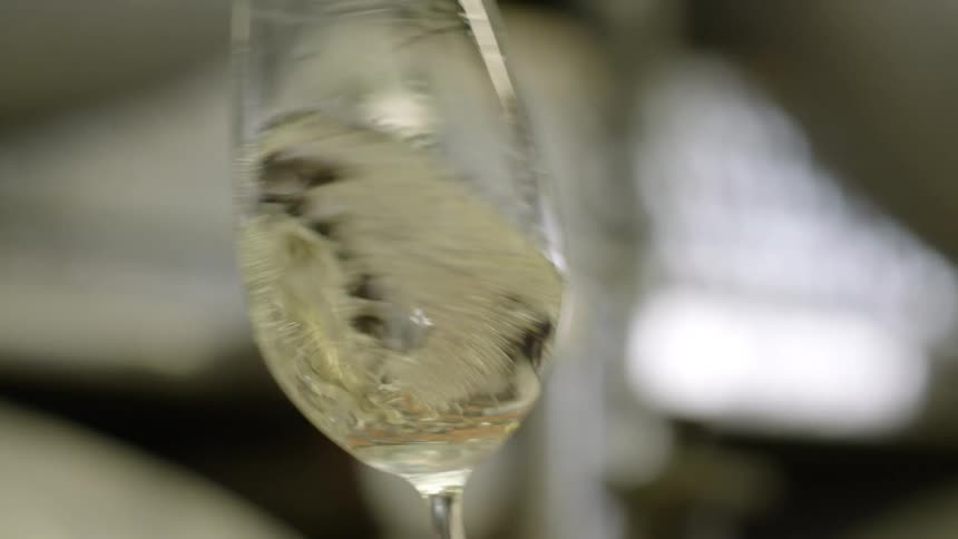 Hand holding a glass of white wine twirling it around in a circular motion