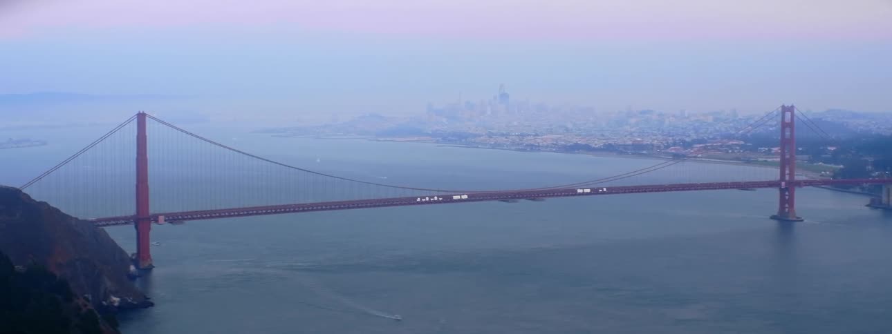 An aerial view of the golden gate bridge with traffic on the bridge in hazy weather conditions
