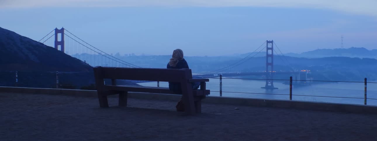 Person sitting on a bench on an overlook looking out at the golden gate bridge