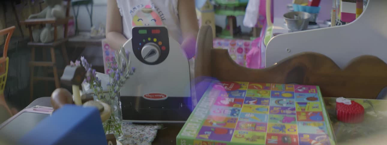Little girl playing indoors at day time with a toy kitchen set in a play room