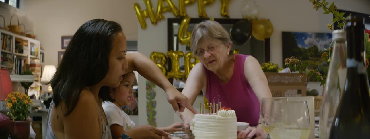 A family is celebrating a birthday and cutting the cake