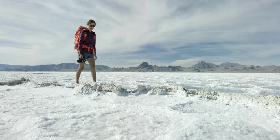 A woman wearing shorts and flip flops as she walks through snow