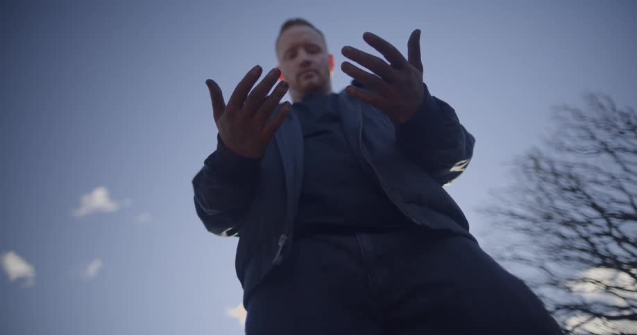A mans head is facing downward to his upward facing palms while his eyes are closed