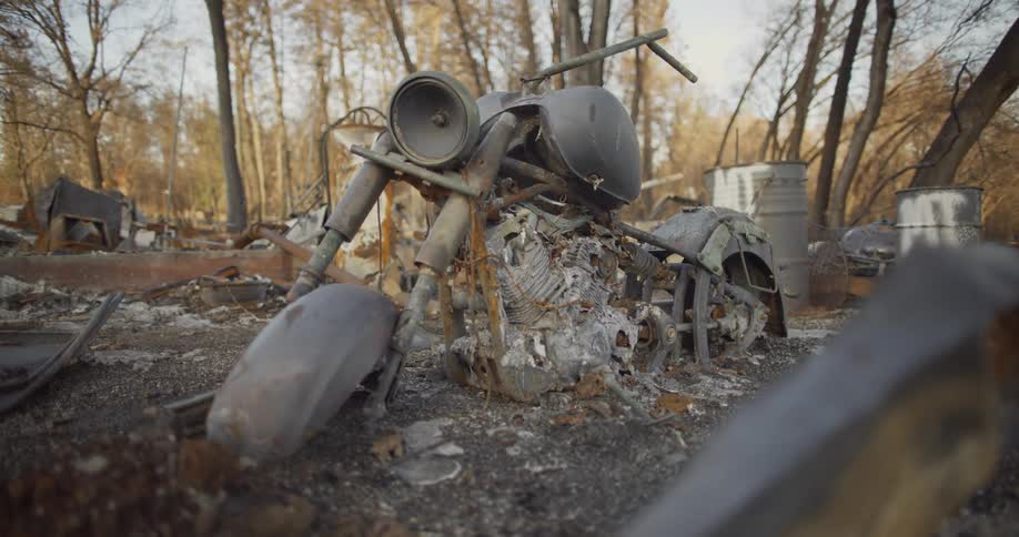 In a junkyard a derelict motorcycle is left broken down and rusting